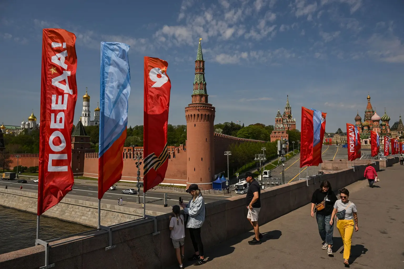 People walk along Moskvoretsky bridge adorned with Victory Day decorations, with the Kremlin and St. Basil's cathedral seen in the background, in central Moscow on May 6, 2026.