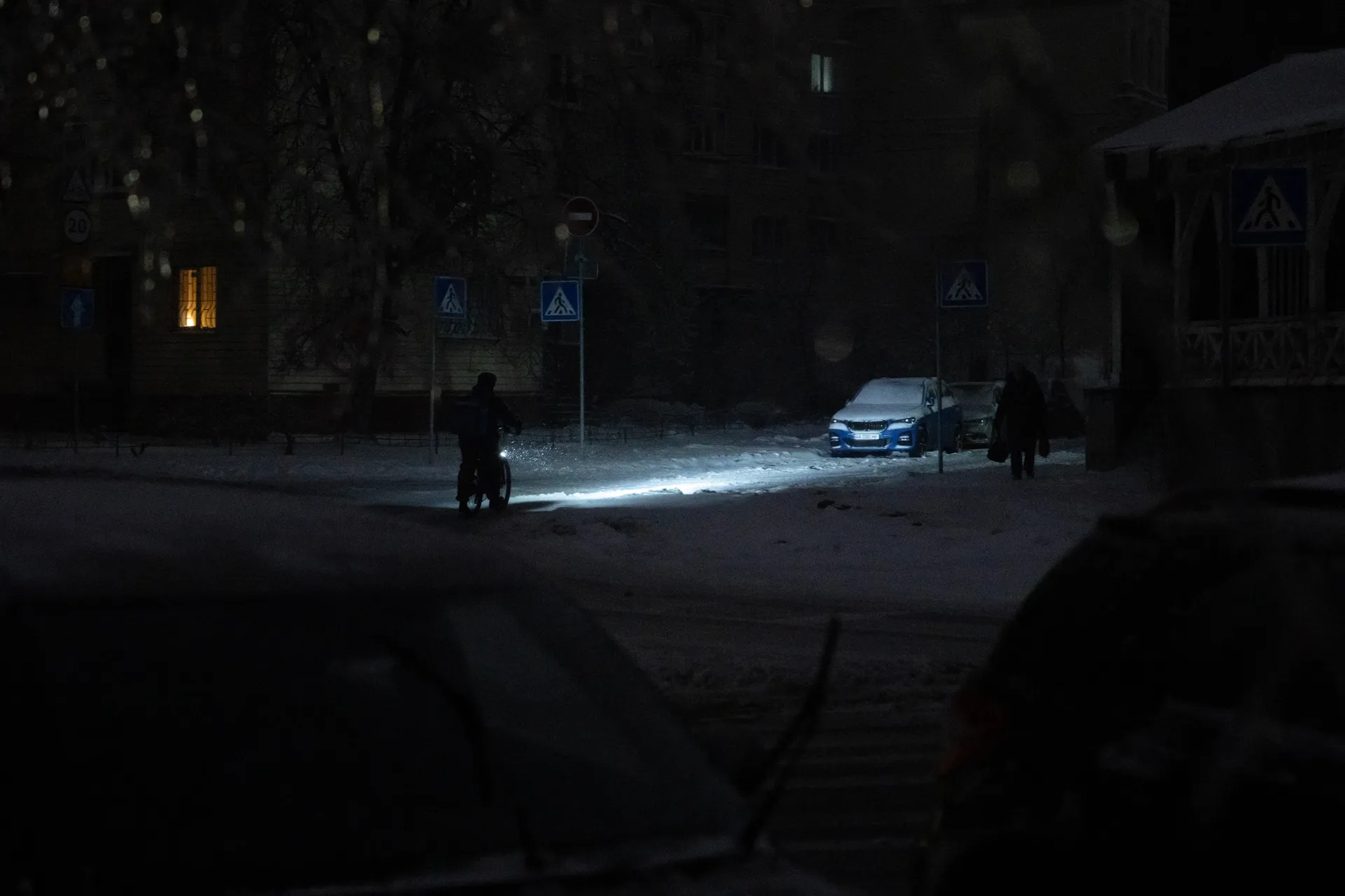 A person riding a bicycle on an unlit street during a power outage in Kyiv, Ukraine